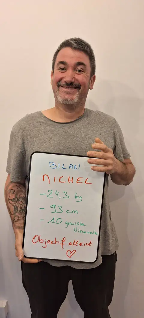 Un membre pose devant une ardoise blanche où sont notées ses mesures de bilan, au club
