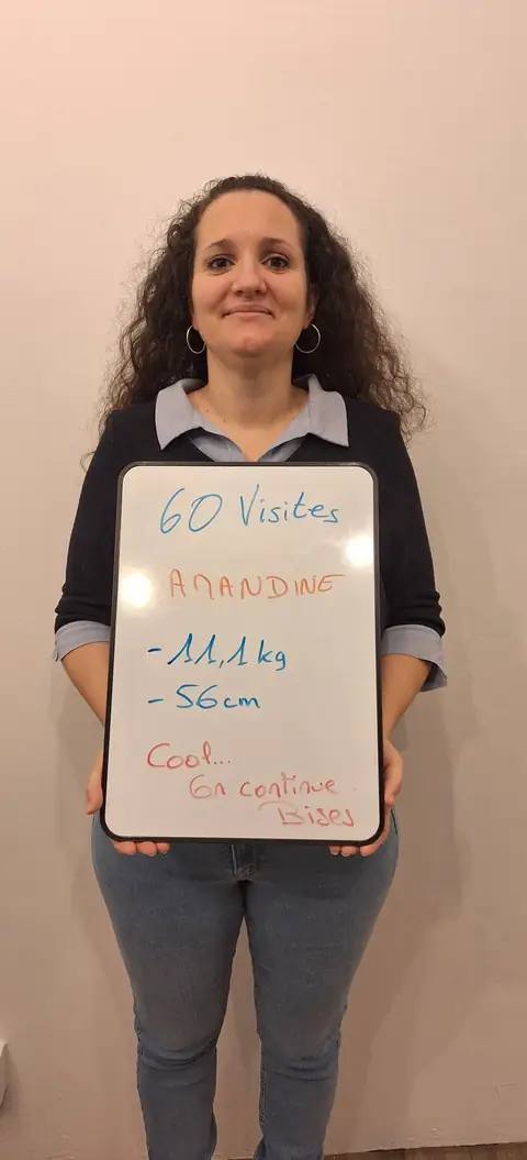 Une membre pose devant une ardoise blanche où sont notées ses mesures de bilan, au club