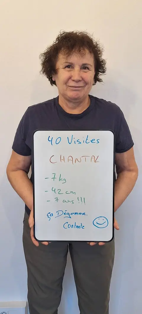 Une membre pose devant une ardoise blanche où sont notées ses mesures de bilan, au club