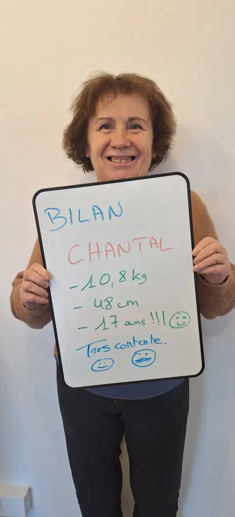 Une membre pose devant une ardoise blanche où sont notées ses mesures de bilan, au club