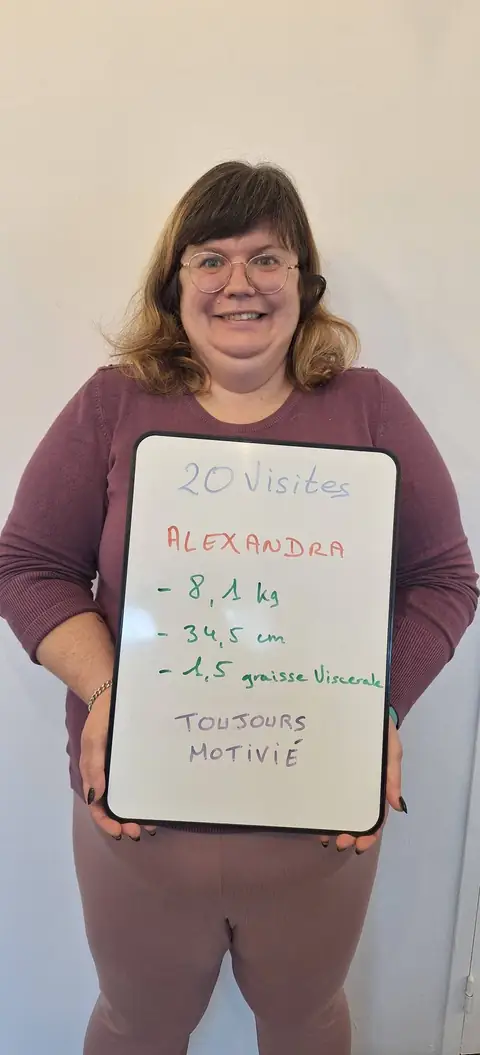 Une membre pose devant une ardoise blanche où sont notées ses mesures de bilan, au club